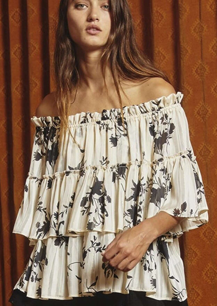 Bucket List Style# T1484 | Ladies Floral Print Tiered Off Shoulder Top with Merrow stitch detailing lurex chiffon in Cream with Black Floral Print | Made in USA