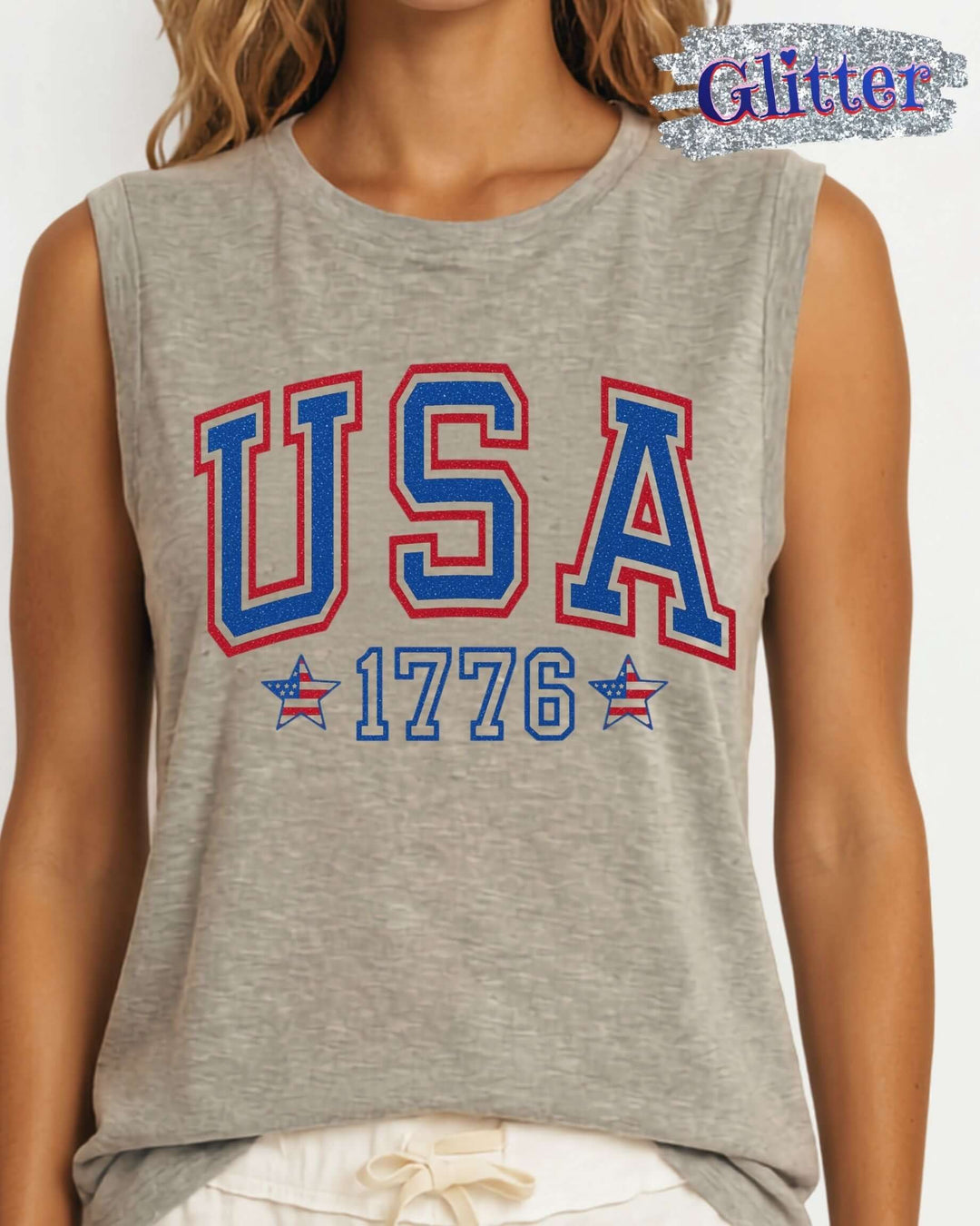 Glitter USA varsity graphic muscle tee with 1776 &amp; flag star accents. Made in USA, relaxed fit, 75% cotton. Perfect for 4th of July. Sizes S-L.