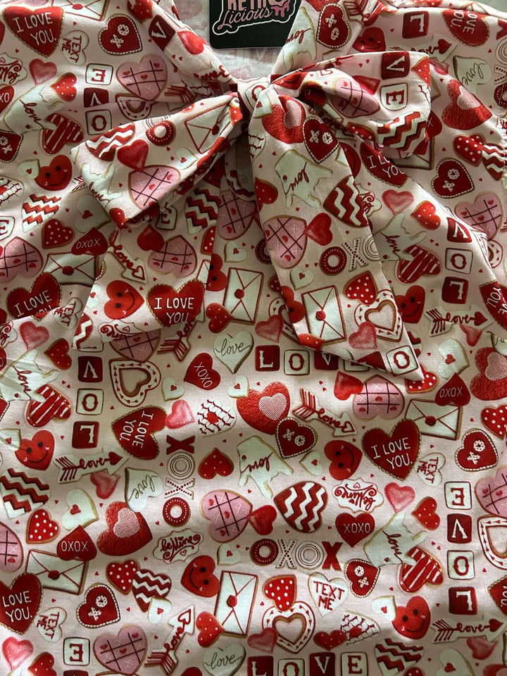 Vintage Tops This top is for the vintage lover at heart! Shown in our XOXO print, this 100% cotton top features bust darts for a flattering silhouette, a side zippered closure for ease of wear, and an oversized bow at the neckline for that perfect 1950's inspired look.