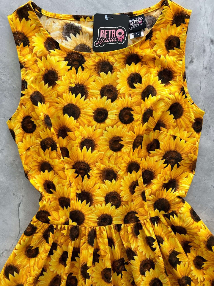 Made in USA by Retrolicious, this 100% cotton sunflower vintage dress features a high neckline, full skirt, pockets, and back zip. Sizes XS–4X.