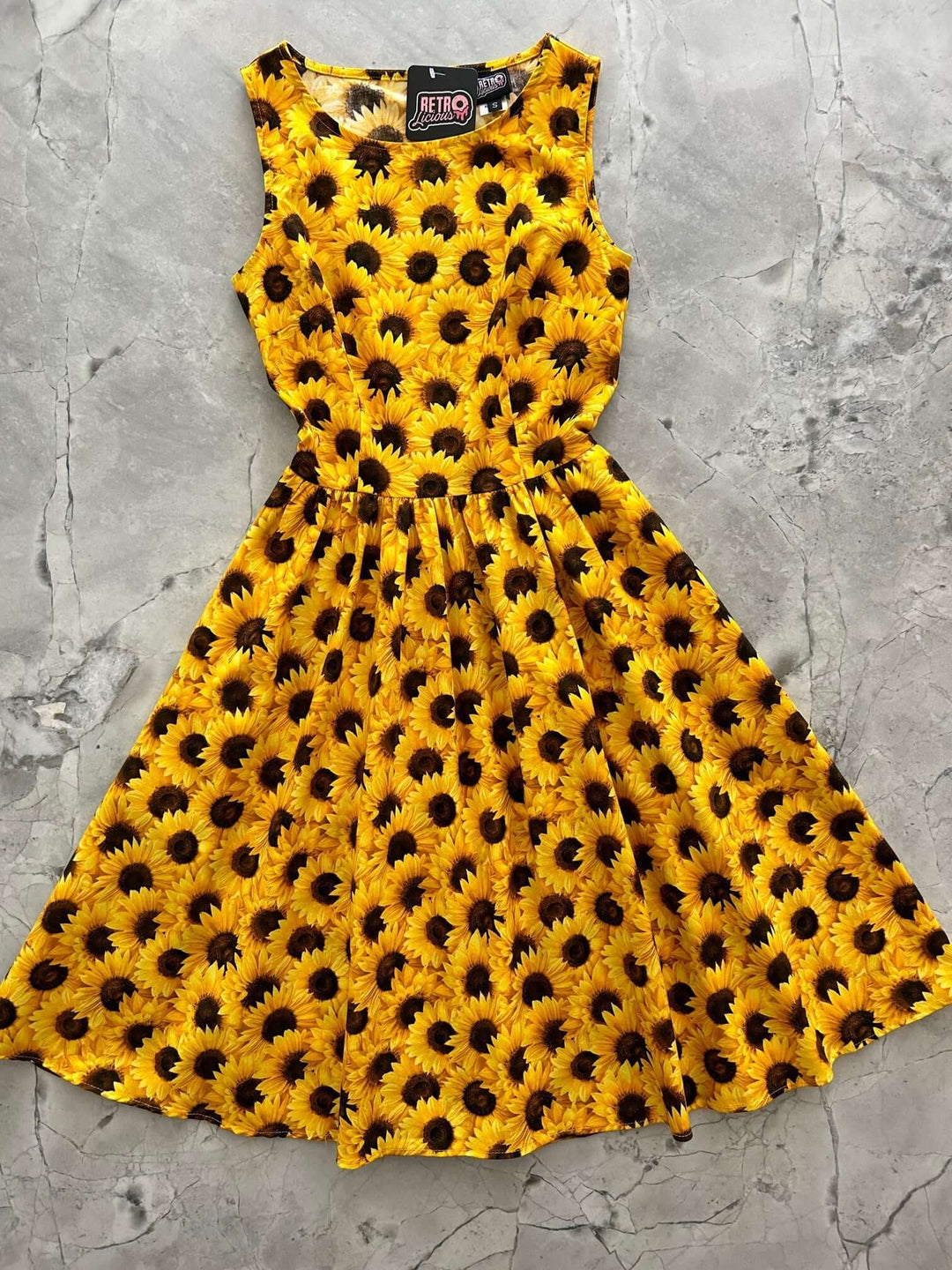 Made in USA by Retrolicious, this 100% cotton sunflower vintage dress features a high neckline, full skirt, pockets, and back zip. Sizes XS–4X.