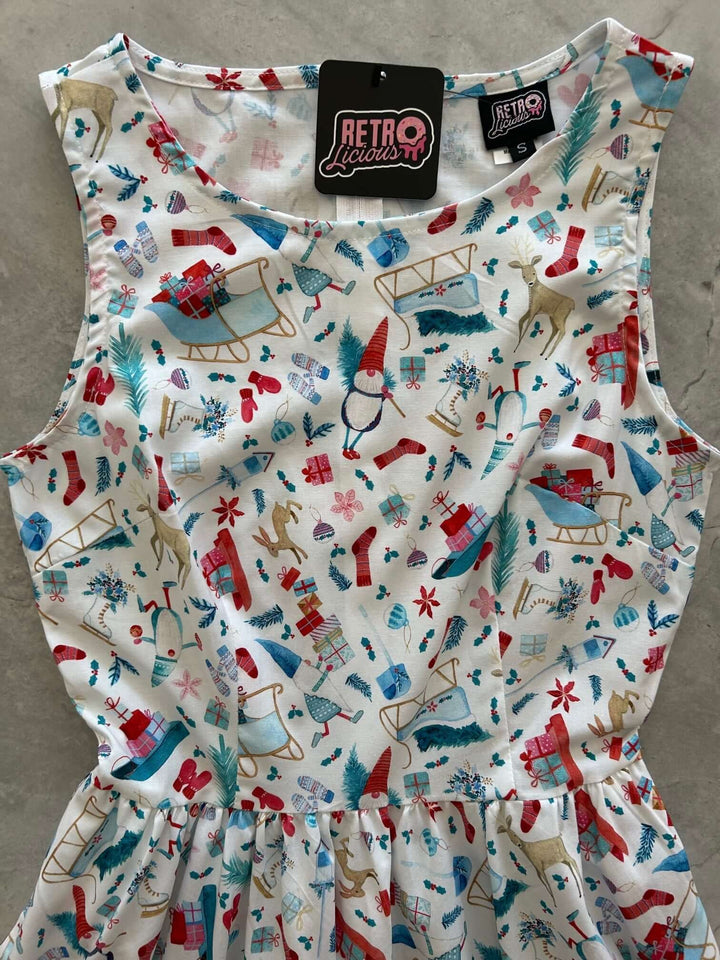 Introducing our Winter Cheer Vintage Dress. This dress boasts a fun and playful print featuring gnomes, sleds, ice skates, mittens, and reindeer. It's a whimsical and festive choice for your winter wardrobe. Spread the joy of the season with this unique and charming piece! A vintage style piece with fun, modern details in our Winter Cheer print. Made from 100% cotton, this classic 1950's inspired dress features a high neckline, longer length skirt with hidden side pockets and back zippered closure.