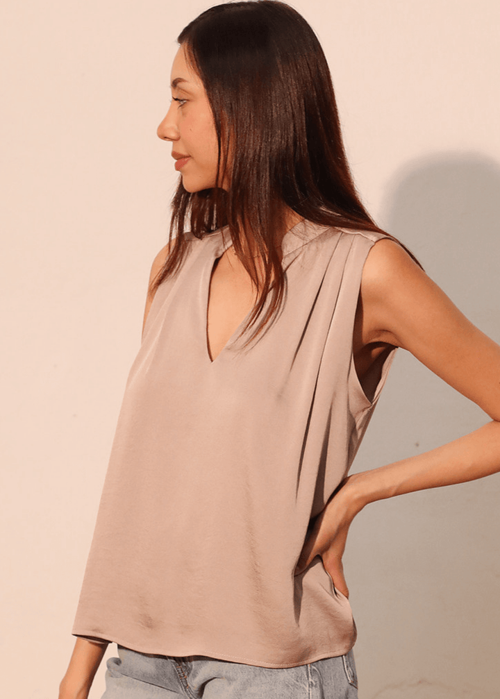Elevate your wardrobe with this sophisticated taupe poly silk top, designed for effortless elegance. The sleeveless silhouette and flattering V-neckline create a refined look, while strategic pleating at the front and back adds subtle dimension and movement. 