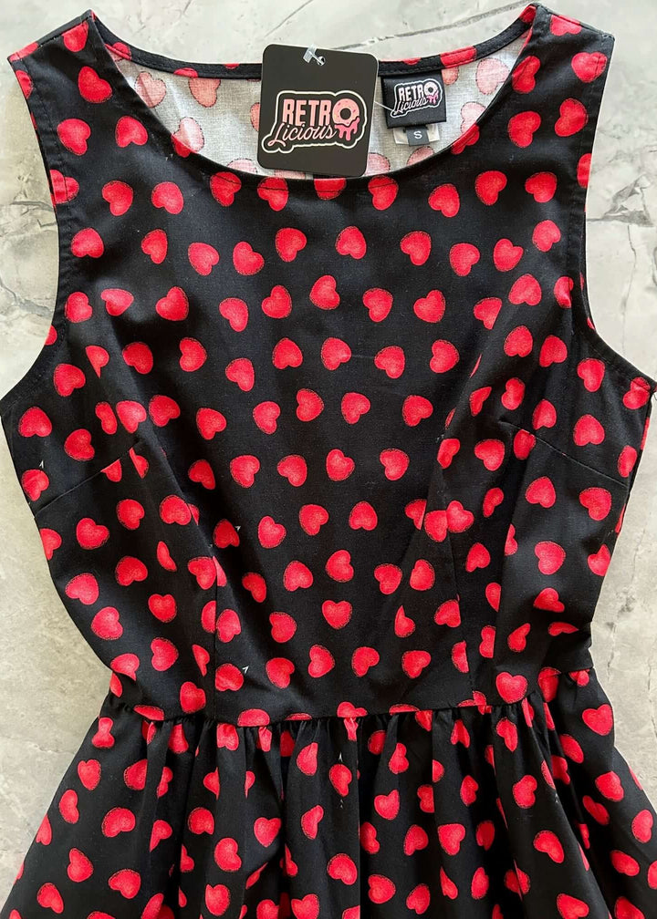 Made in USA, A women's vintage style piece with fun, modern details; our midi dress is now available in our Hearts print. Made from 100% cotton, this classic 1950's inspired dress features a high neckline, longer length swing skirt with hidden side pockets, and back zippered closure. 