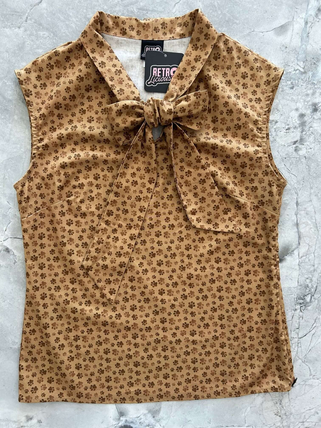 Vintage Style Tops This top is for the vintage lover at heart! Now available in our Paw print. This 100% cotton top features bust darts for a flattering silhouette, a side zippered closure for ease of wear, and an oversized bow at the neckline for that perfect 1950's inspired look.