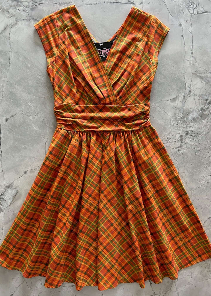 Made in USA The Greta is everything you could want and more! Shown in our Orange Plaid print, this vintage style cotton knee length dress features a gathered surplice neckline, cummerbund waist with figure flattering gathers, a vintage inspired twirl-worthy skirt with hidden side pockets, and a back zippered closure.