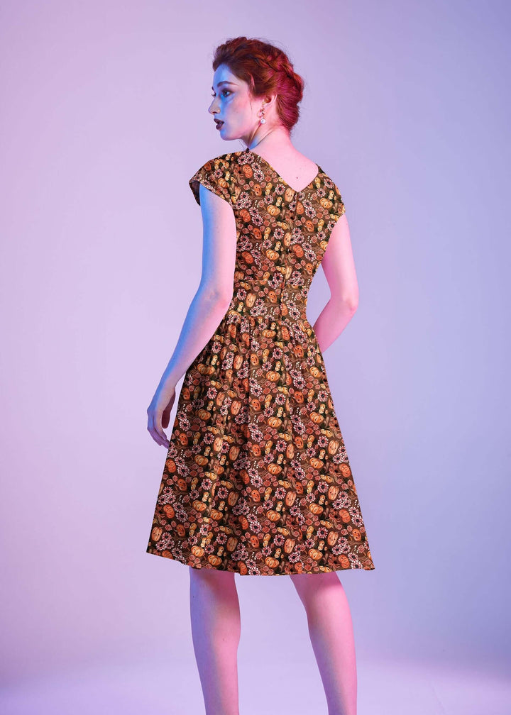 Made in USA by Retrolicious, 100% cotton Greta dress with a V-neck, gathered waist, pockets, and a playful pumpkin-floral print. Sizes XS–4X.