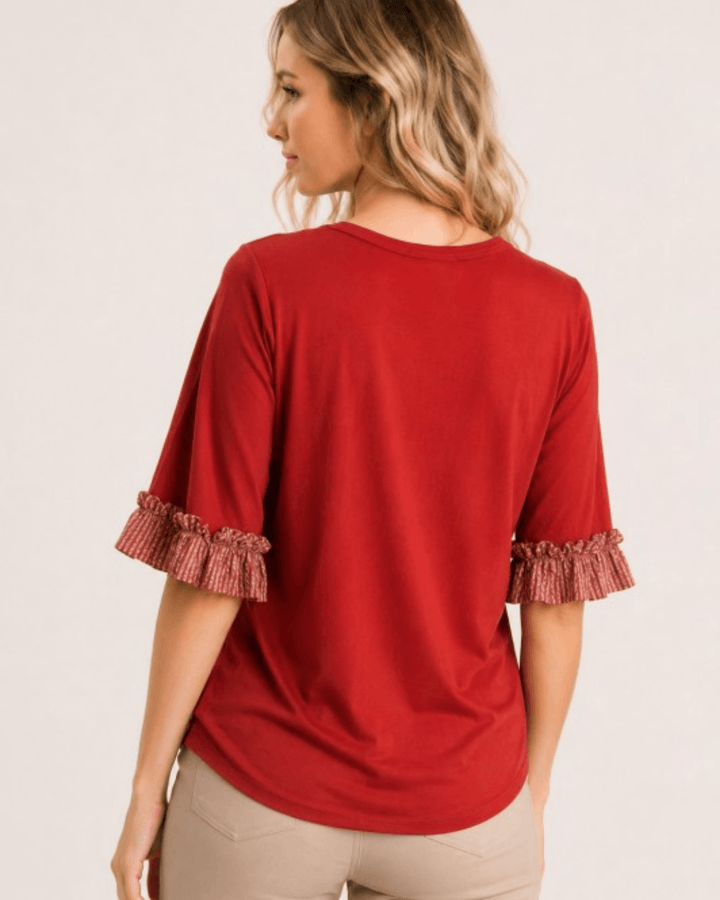 Made in USA rust knit top with printed contrast ruffle sleeves, back view styled with tan trousers