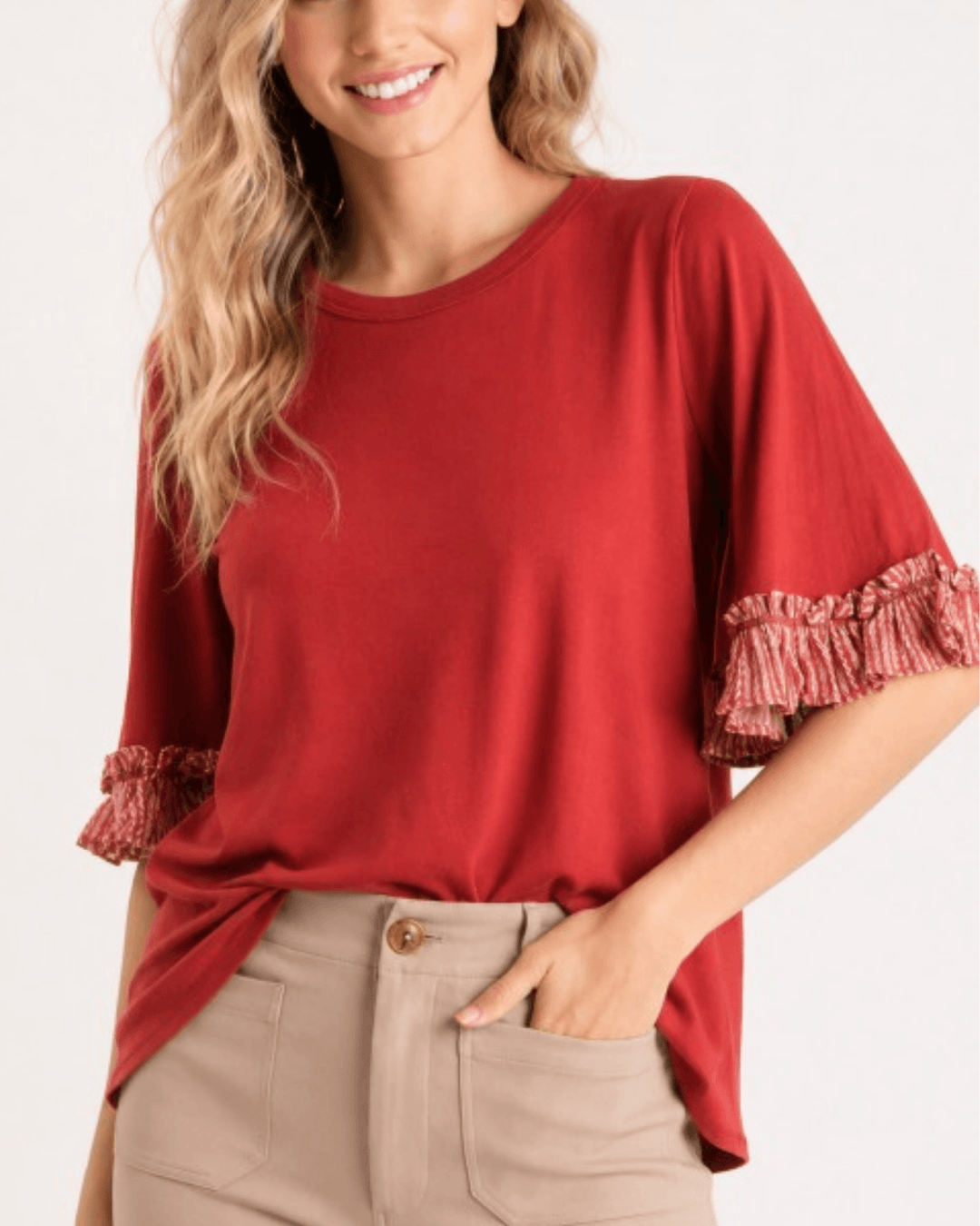 Made in USA rust knit top with round neckline and printed contrast ruffle sleeves, front view styled with tan trousers