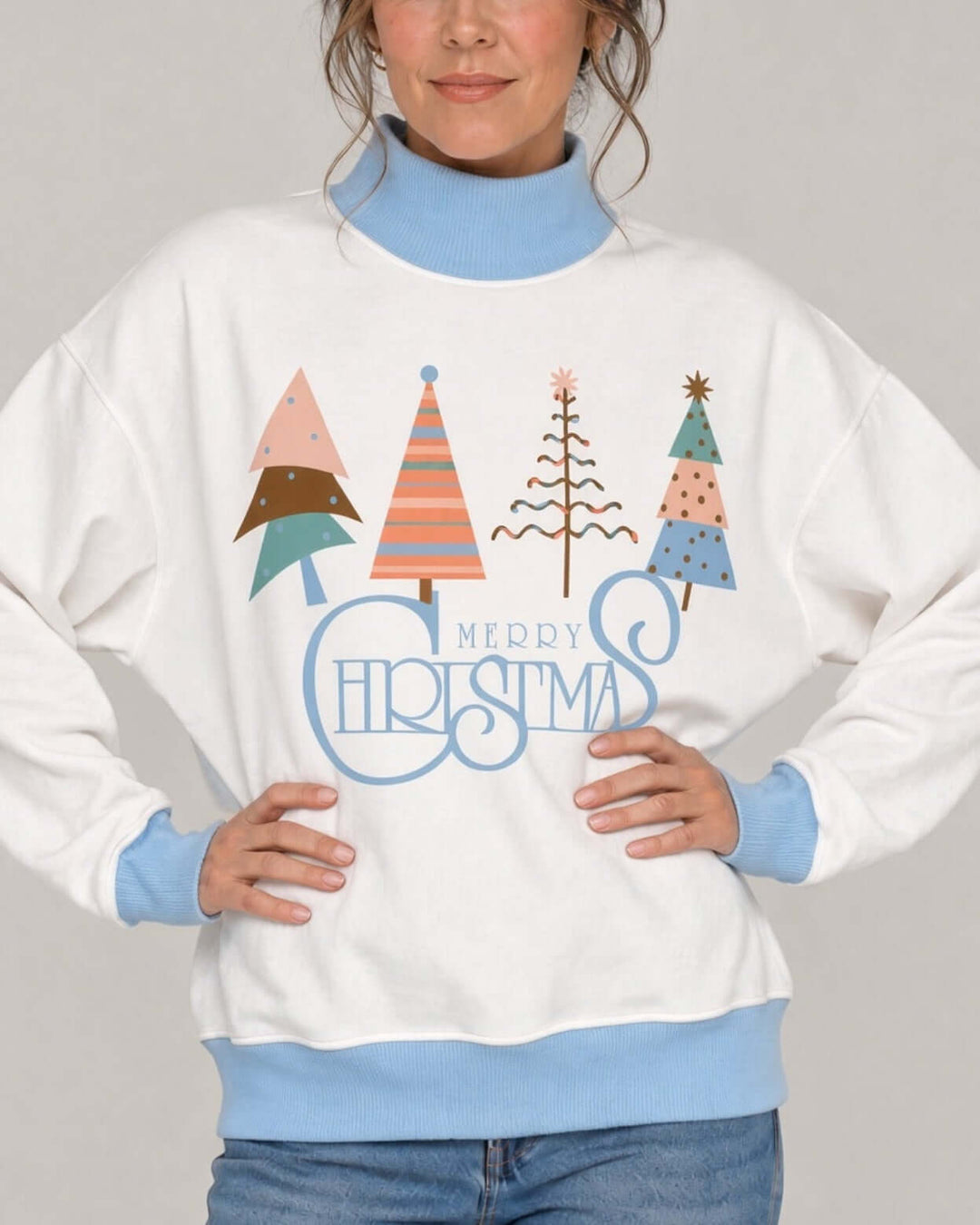 Women's white oversized mock neck sweatshirt with light blue ribbed trim featuring the Artsy Christmas Tree Graphic design, front close-up, hands on hips, Made in USA