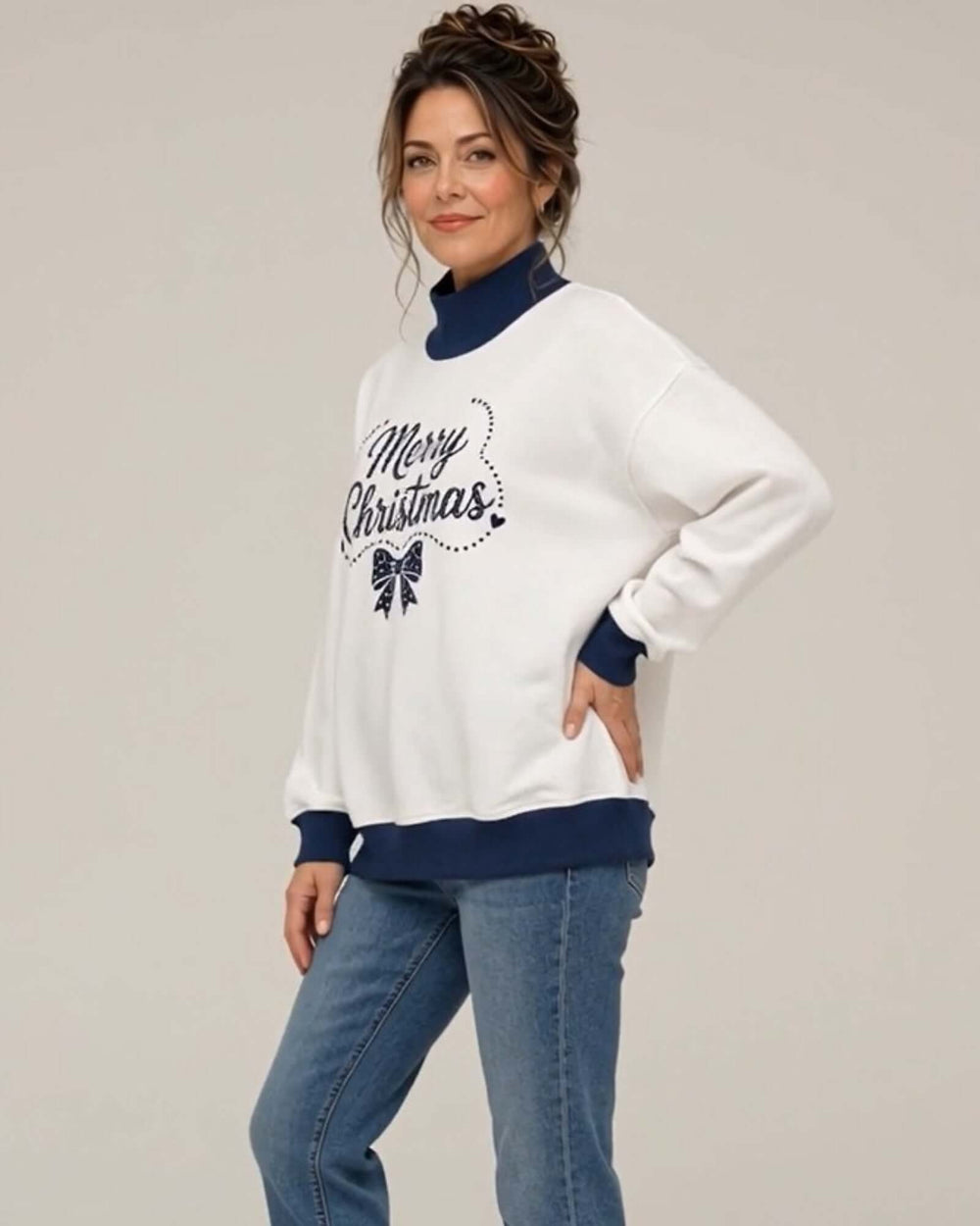 Women's white oversized mock neck sweatshirt with navy ribbed trim featuring the Navy Christmas Bow design, side-angled view, hand on hip, Made in USA