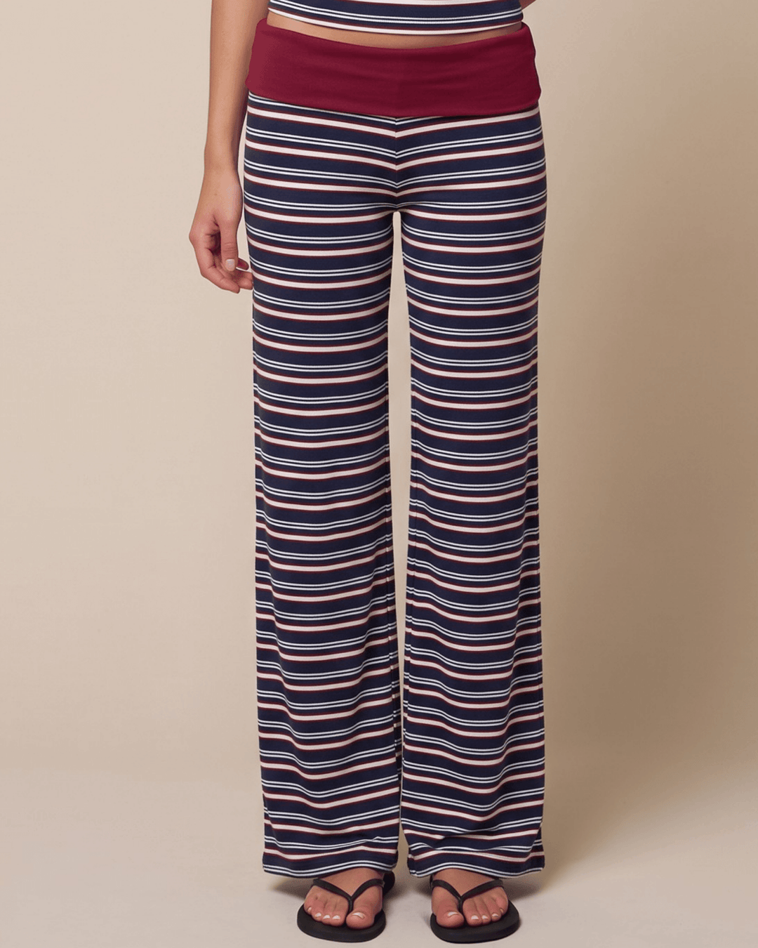 A woman wearing Made in USA striped pajama set with a fitted tank, fold-over waistband, and relaxed wide-leg pants in burgundy, navy, and white. Super soft and stretchy fabric.