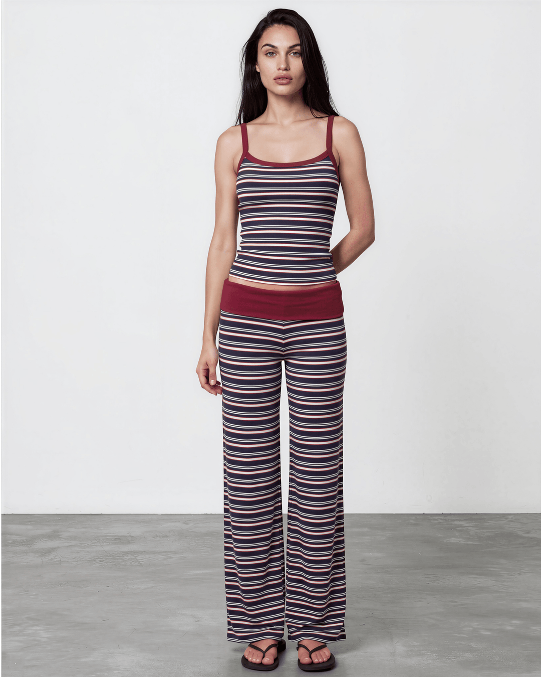 A woman wearing Made in USA striped pajama set with a fitted tank, fold-over waistband, and relaxed wide-leg pants in burgundy, navy, and white. Super soft and stretchy fabric.