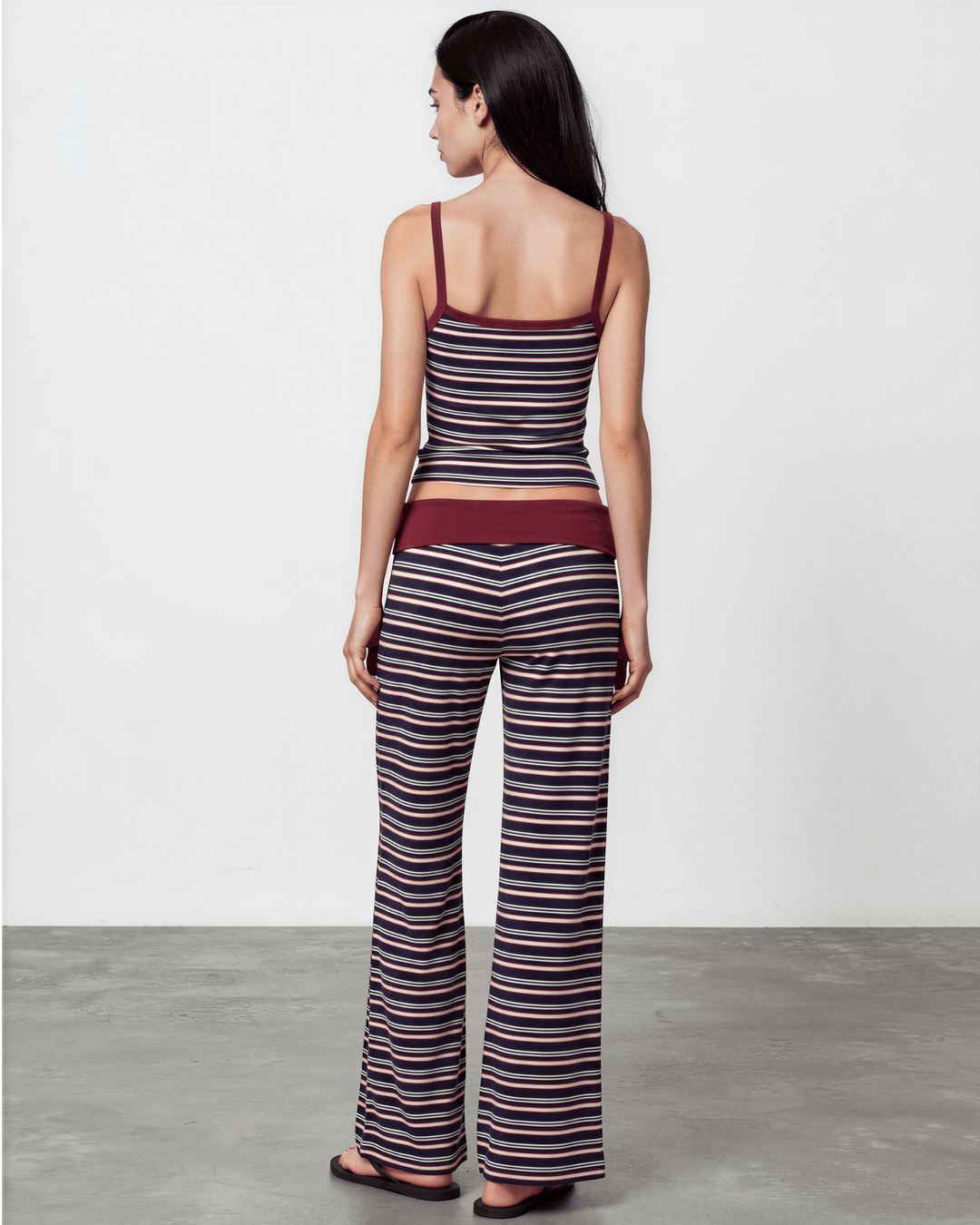 A woman wearing Made in USA striped pajama set with a fitted tank, fold-over waistband, and relaxed wide-leg pants in burgundy, navy, and white. Super soft and stretchy fabric.