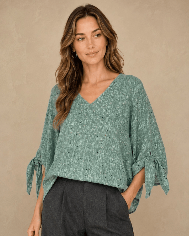 Made in USA. Green confetti dot chevron blouse with a V-neck, dolman sleeves and adjustable cuff ties. Lightweight woven fabric with a loose, flowing fit.