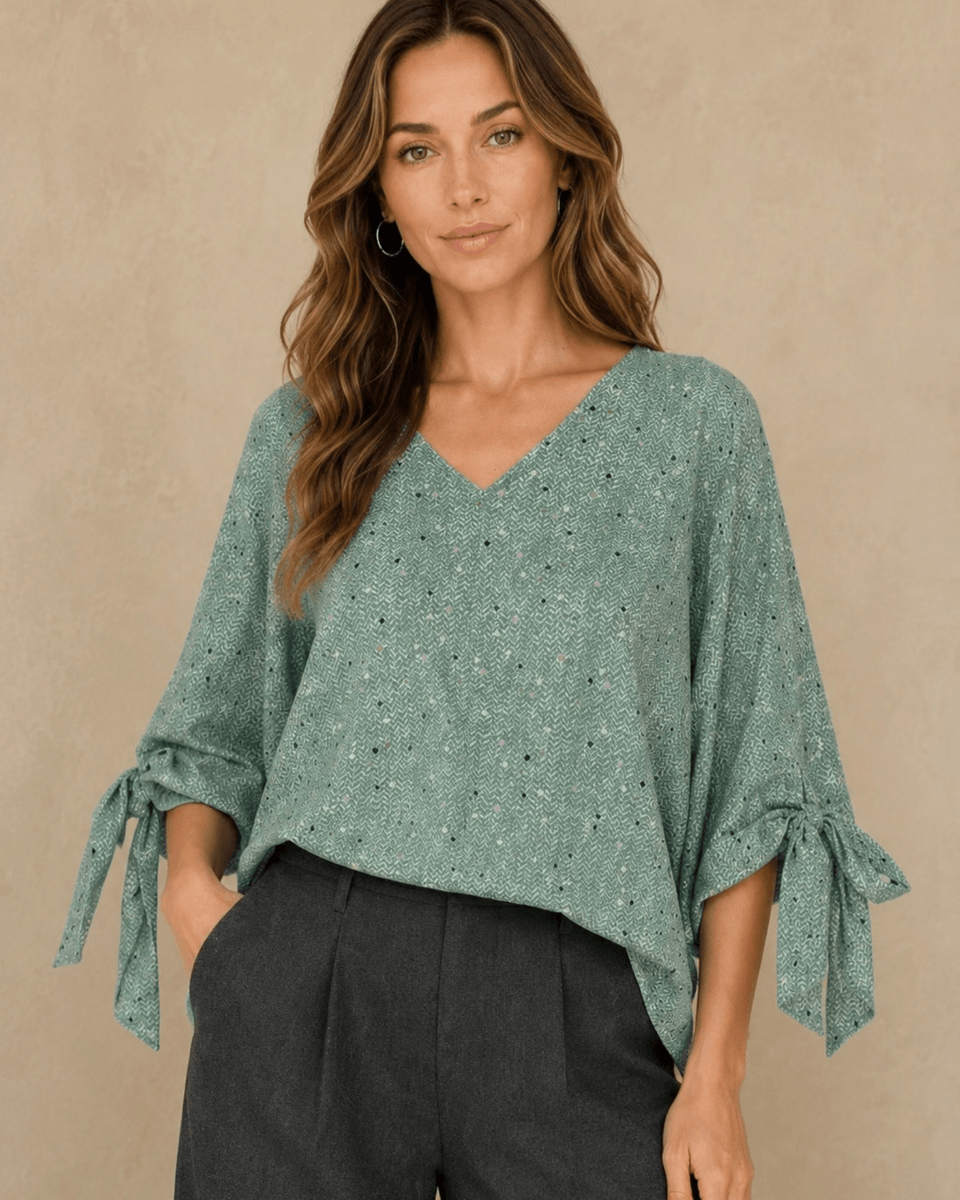 Made in USA. Green confetti dot chevron blouse with a V-neck, dolman sleeves and adjustable cuff ties. Lightweight woven fabric with a loose, flowing fit.
