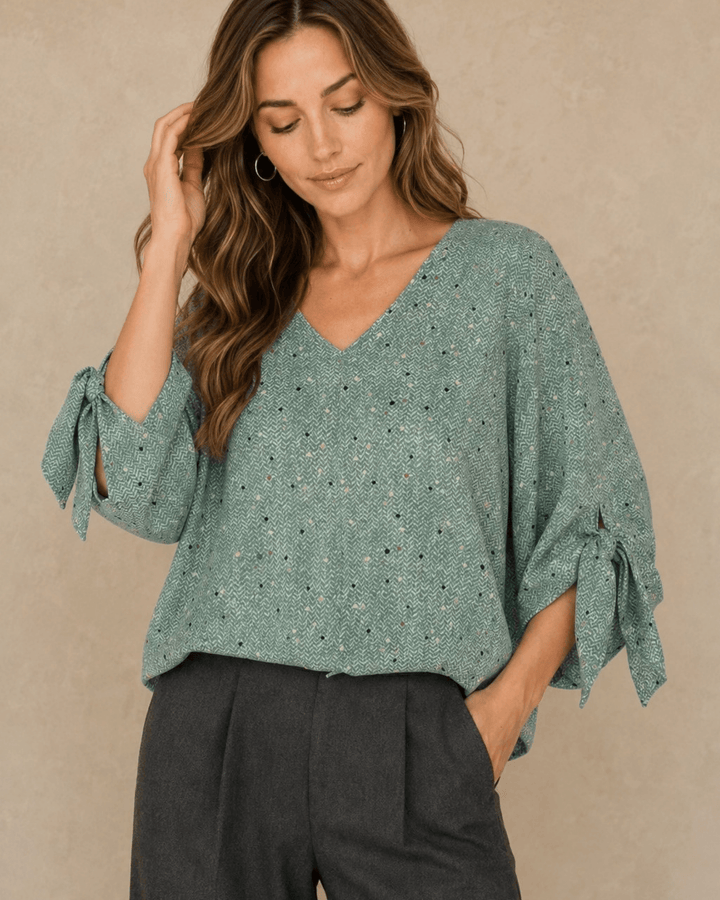 Made in USA. Green confetti dot chevron blouse with a V-neck, dolman sleeves and adjustable cuff ties. Lightweight woven fabric with a loose, flowing fit.