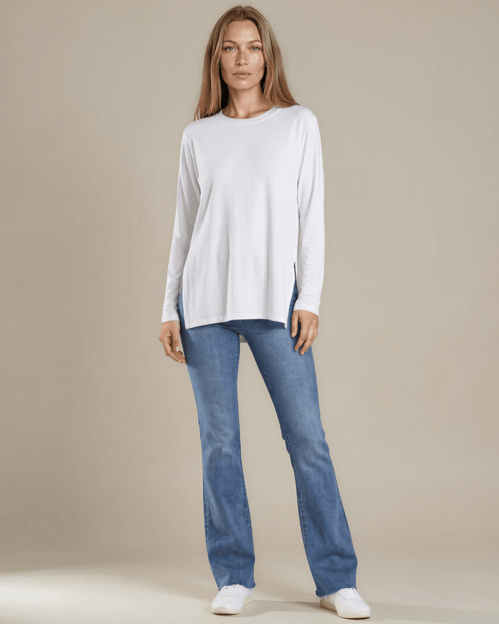 Made in USA. White long sleeve cotton top with a crew neck, relaxed fit and side slits. Soft 95% cotton with stretch for easy everyday layering.