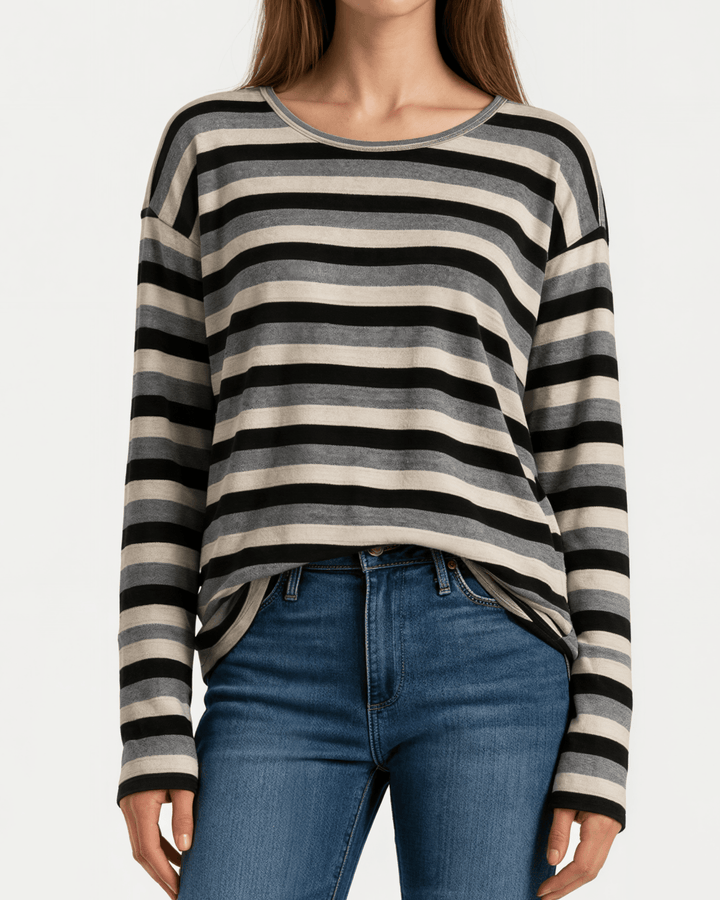 Made in USA Stella women’s grey, black, and cream striped long sleeve top with a round neckline, dropped shoulders, relaxed oversized fit, and rounded hem.