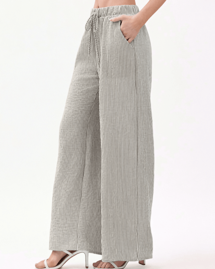 Charcoal and off-white vertical pinstripe seersucker wide leg pants with a soft crinkled texture, elastic drawstring waistband, and side pockets in a relaxed flowy silhouette. Made in USA