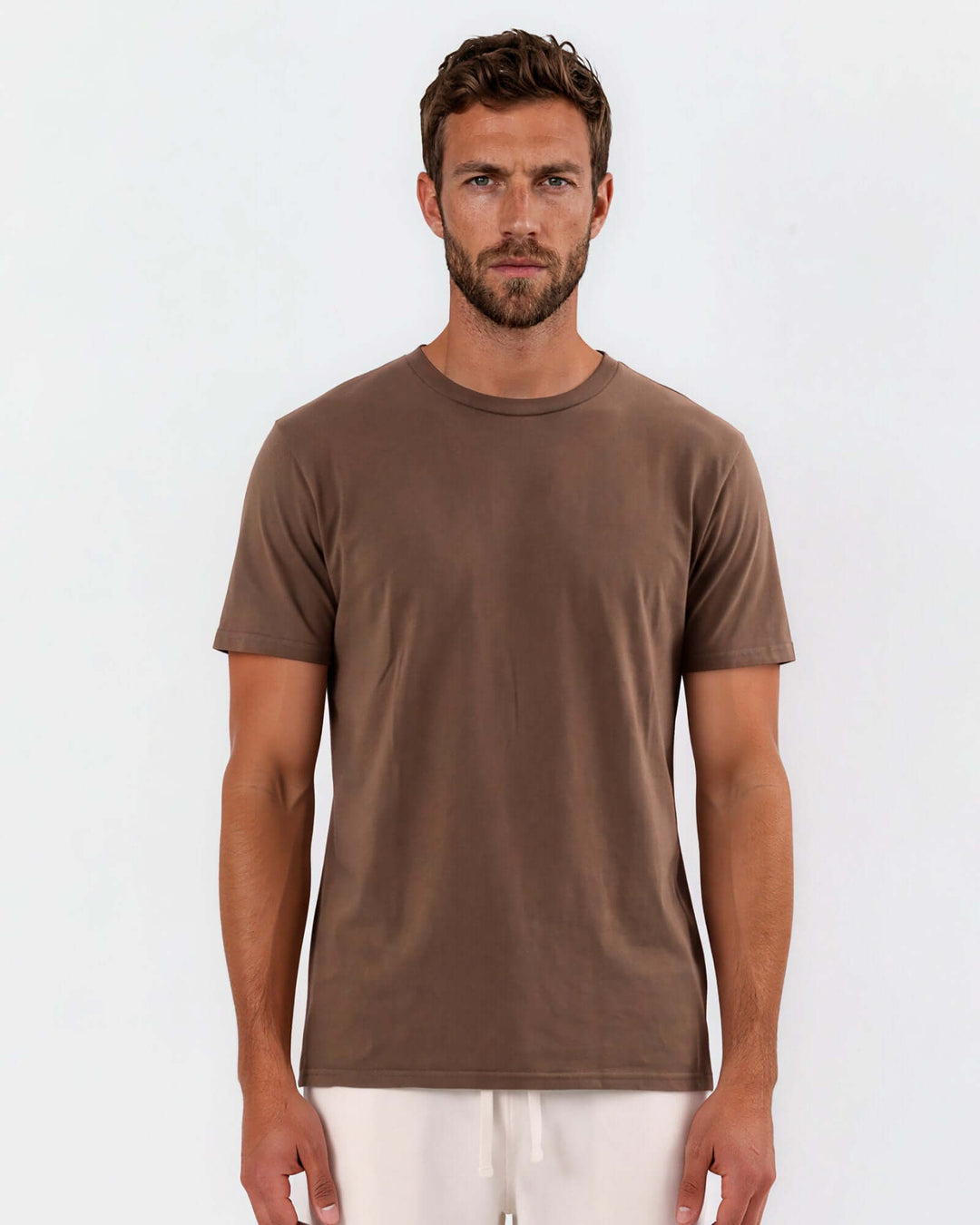 Made in USA Vintage Pigment Dyed Softest Tee - Java: front view of brown crew neck tee on male model with cream pants, studio