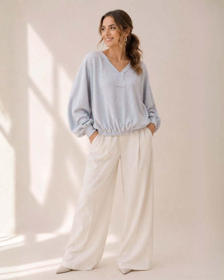 Light blue grey textured knit pullover with bubble sleeves, raw edge V-neck &amp; elastic waist hem. 60% poly 40% cotton. Made in USA. Sizes S–L.