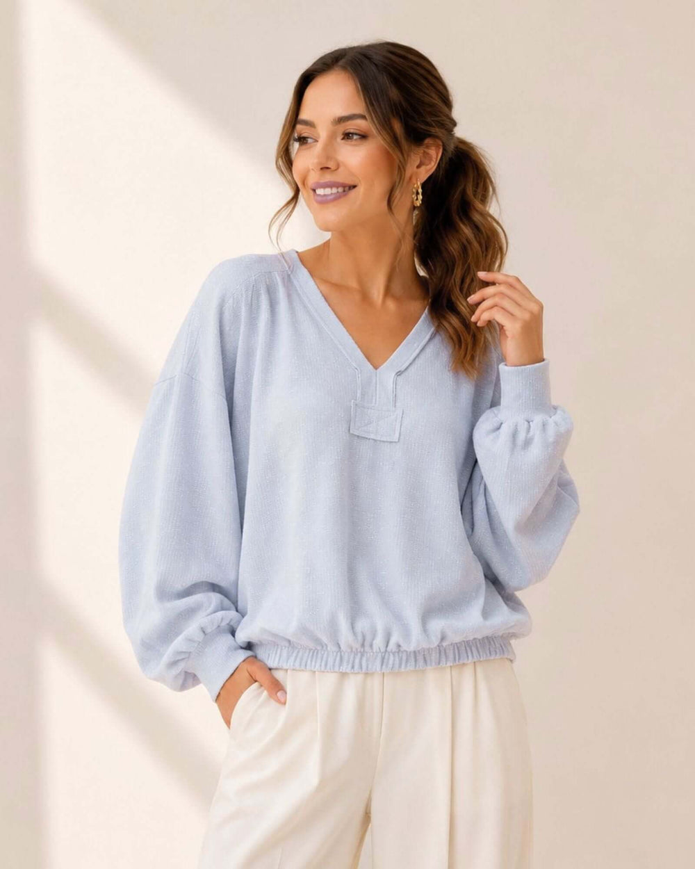 Light blue grey textured knit pullover with bubble sleeves, raw edge V-neck & elastic waist hem. 60% poly 40% cotton. Made in USA. Sizes S–L.