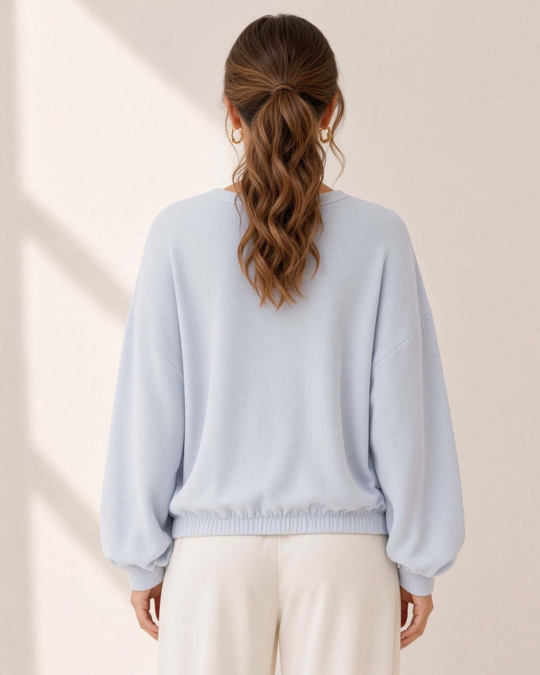 Light blue grey textured knit pullover with bubble sleeves, raw edge V-neck &amp; elastic waist hem. 60% poly 40% cotton. Made in USA. Sizes S–L.