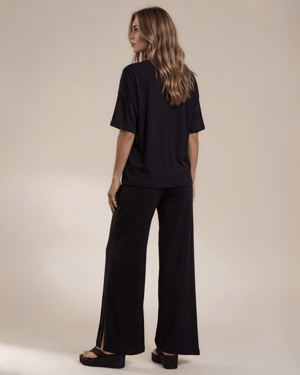 "Black two-piece loungewear set featuring a relaxed-fit short-sleeve crew neck tee with a chest pocket and wide-leg pants with split hems and an elastic waistband, in a soft stretch fabric blend. Made in USA."