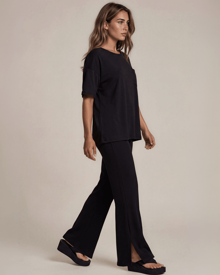 "Black two-piece loungewear set featuring a relaxed-fit short-sleeve crew neck tee with a chest pocket and wide-leg pants with split hems and an elastic waistband, in a soft stretch fabric blend. Made in USA."