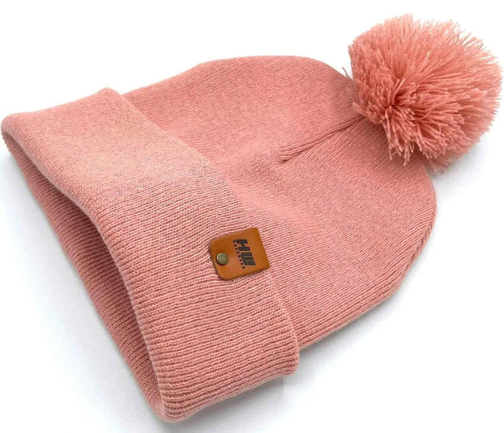 Keep warm and stylish with the HAAKWEAR PomPom Beanie in Pearl Pink, proudly made in the USA. This cozy beanie is perfect for adding a touch of fashion to your winter wardrobe. . Made from 100% Acrylic.