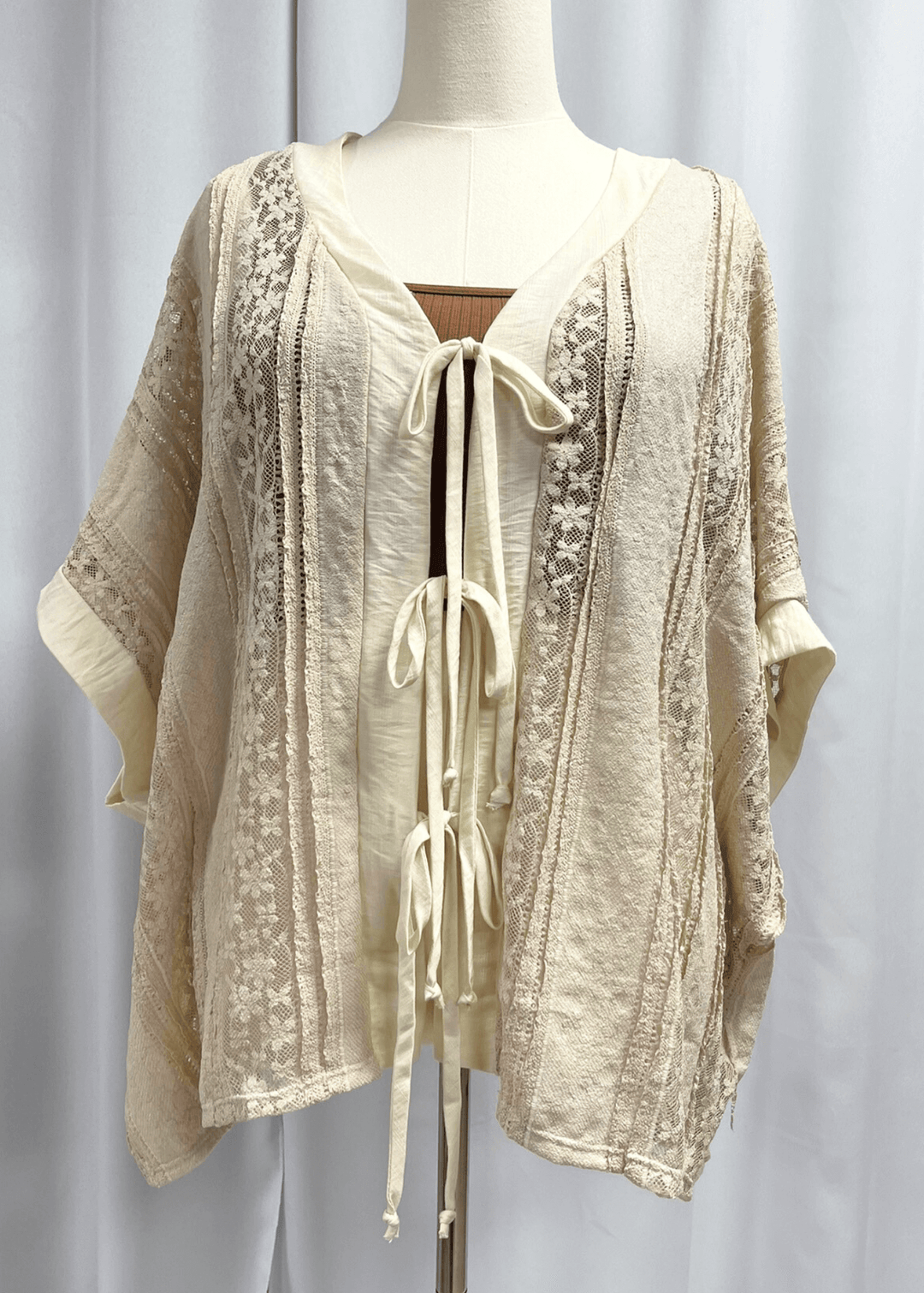 Elevate your wardrobe with this charming Daisy Lace Tie Front Top in cream, crafted right here in the USA. The oversized silhouette features delicate floral lace with a flattering V-neckline and three functional front ties for customizable styling. 