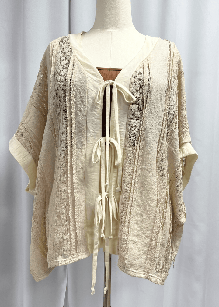 Elevate your wardrobe with this charming Daisy Lace Tie Front Top in cream, crafted right here in the USA. The oversized silhouette features delicate floral lace with a flattering V-neckline and three functional front ties for customizable styling. 