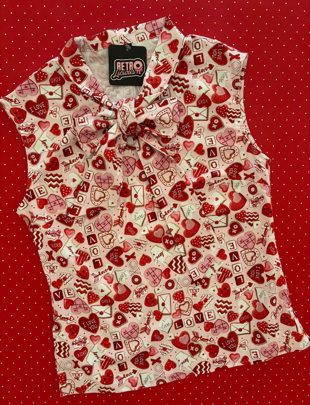 Vintage Tops This top is for the vintage lover at heart! Shown in our XOXO print, this 100% cotton top features bust darts for a flattering silhouette, a side zippered closure for ease of wear, and an oversized bow at the neckline for that perfect 1950's inspired look.