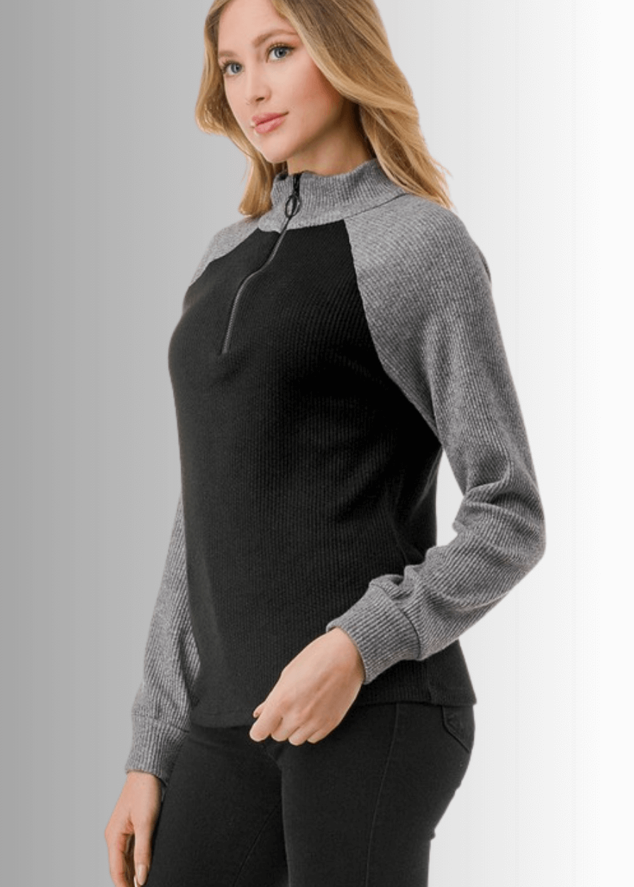 This Paige Color Block Zip Detail Top offers a sleek, semi-fitted silhouette crafted from medium-weight fabric, perfect for layering or standalone wear. Featuring a stylish quarter zip front and a modern black and gray color block design, it combines comfort with contemporary appeal. Made in the USA