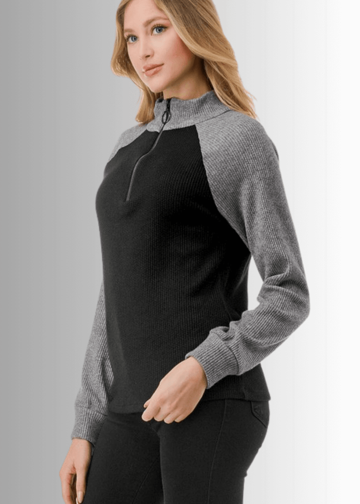 This Paige Color Block Zip Detail Top offers a sleek, semi-fitted silhouette crafted from medium-weight fabric, perfect for layering or standalone wear. Featuring a stylish quarter zip front and a modern black and gray color block design, it combines comfort with contemporary appeal. Made in the USA