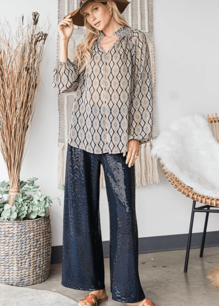 The Olivia Sheer Mock Stand Collar Blouse combines elegant design with lightweight comfort. Crafted from delicate chiffon in a taupe and black geometric print, it features a smocked high collar with a subtle split neckline for refined detail. Long puff sleeves with elasticized cuffs create a soft, graceful shape, complemented by a loose fit and curved hem for effortless sophistication. Made in the USA, this blouse is perfect for elevating any ensemble with a touch of modern elegance. Bucket List Style# T104