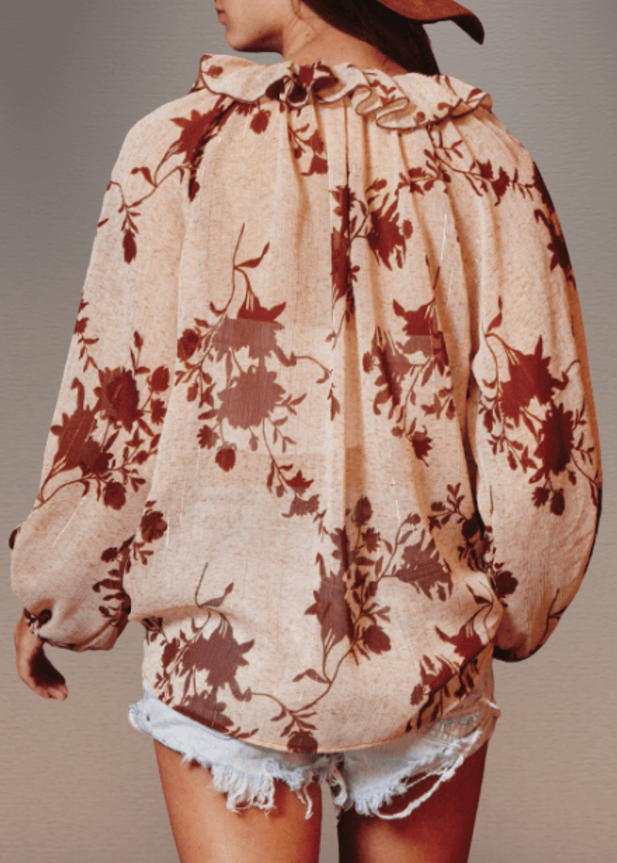 The Presley Lurex Chiffon Floral Ruffle Collar Blouse showcases a sophisticated sheer design in a tan and brown floral print. Its standout smocked high collar and split neckline create an elegant focal point, while long puff sleeves with elasticized cuffs provide refined structure and comfort.  Bucket List Style T1841