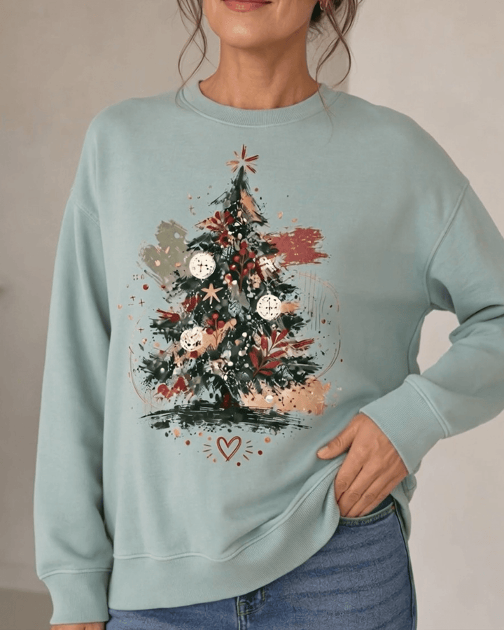 Made in USA Abstract Art Christmas Tree crew neck sweatshirt in sage green with a painterly abstract art Christmas tree graphic, close-up front view of the tree graphic on female model with jeans