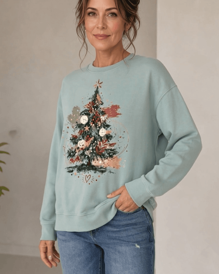 Made in USA Abstract Art Christmas Tree crew neck sweatshirt in sage green with a painterly abstract art Christmas tree graphic, front view with hand in pocket on female model with jeans