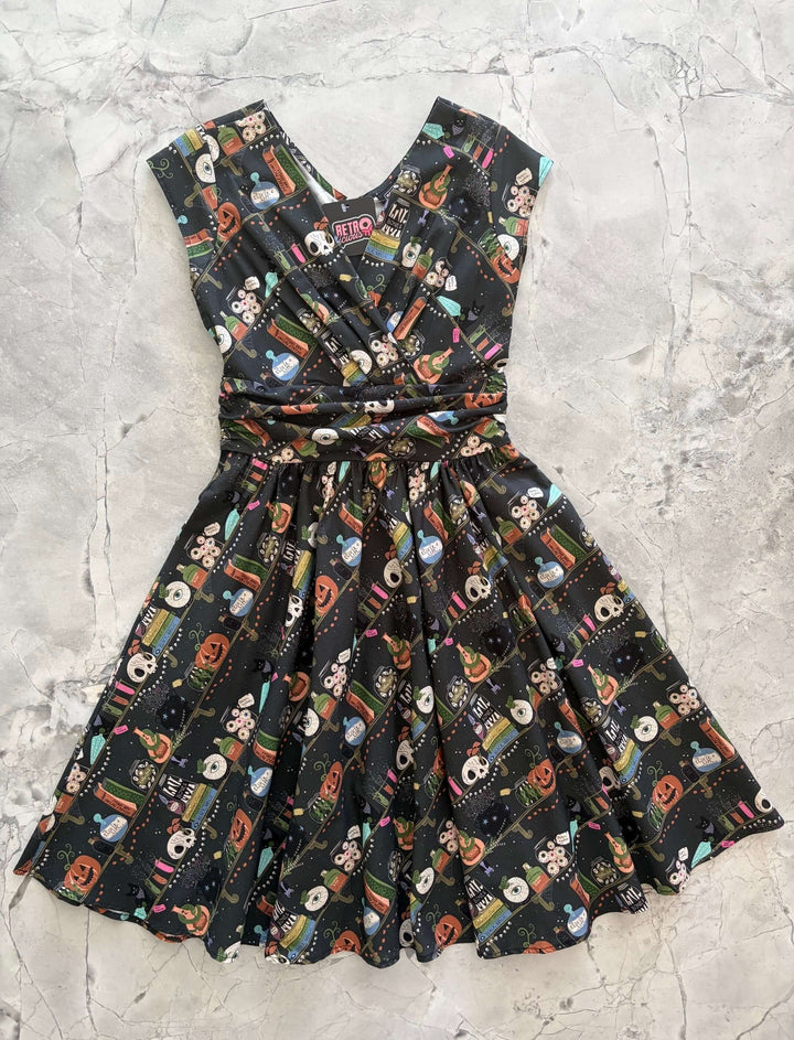 Made in USA, the Retrolicious Potions Greta dress is 100% cotton with a V-neck, gathered waist, pockets, and a true-to-size fit. Sizes XS–4X.