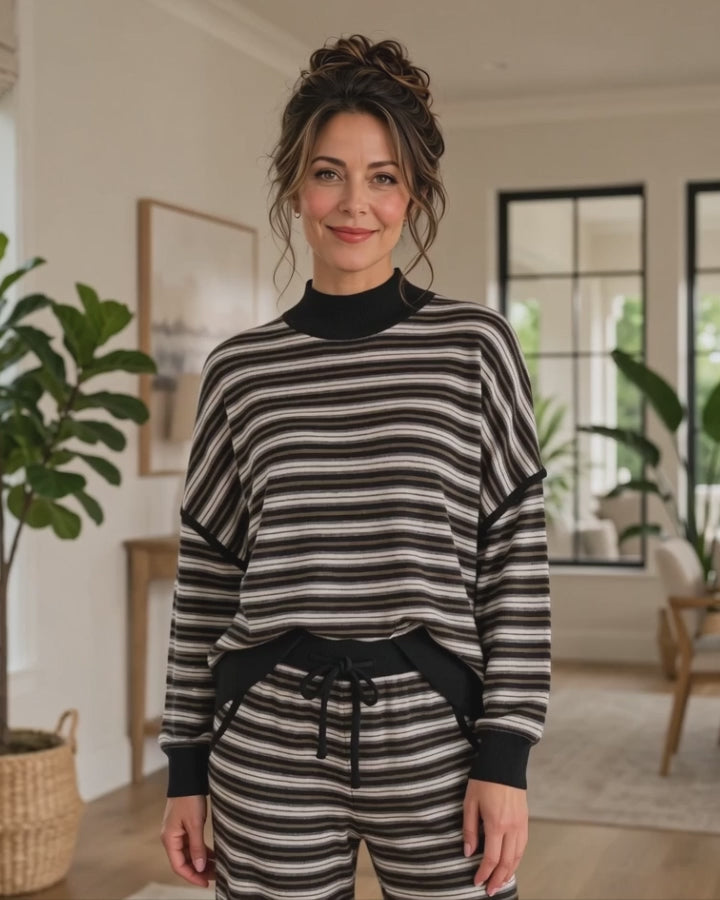 Model wearing the Striking Stripes black and gray striped mock neck top with matching ankle length drawstring pants in a living room, Made in USA