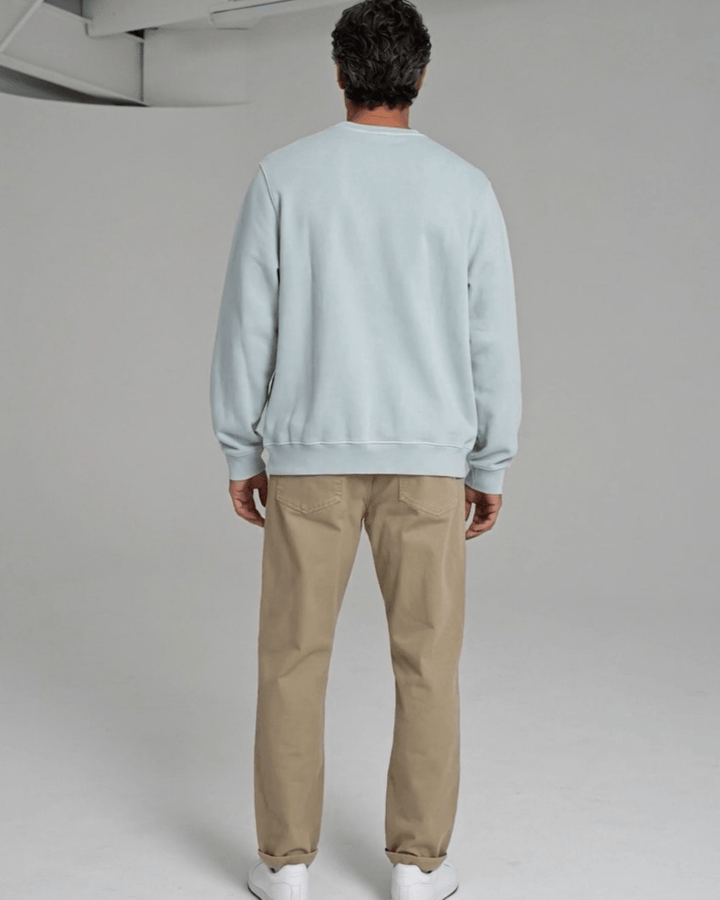 Made in USA Strength and Purpose Holiday Design crew neck sweatshirt in light blue with a Strength and Purpose holiday graphic with navy evergreens and a gold star, back view with a plain back on male model with khaki pants