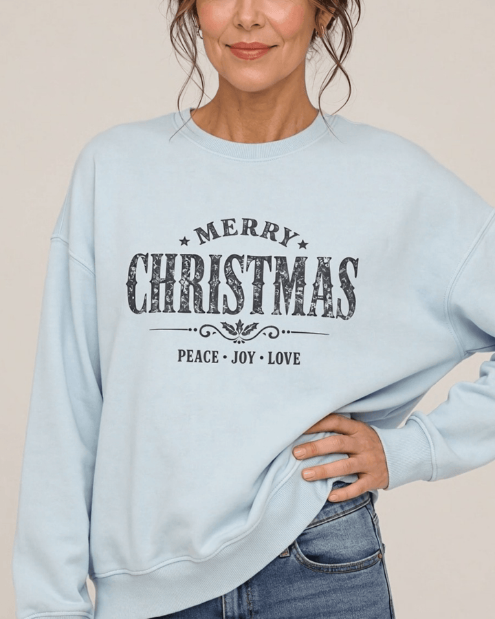 Made in USA Vintage Distressed Merry Christmas crew neck sweatshirt in light blue with a distressed charcoal MERRY CHRISTMAS graphic with PEACE JOY LOVE, close-up front view on female model with jeans