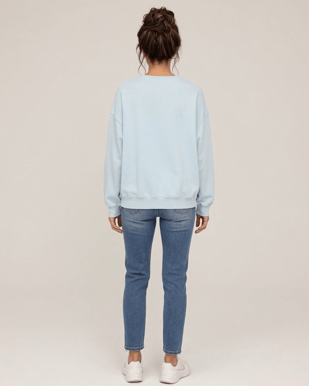 Made in USA Vintage Distressed Merry Christmas crew neck sweatshirt in light blue with a distressed charcoal MERRY CHRISTMAS graphic with PEACE JOY LOVE, back full-length view with a plain back on female model with jeans