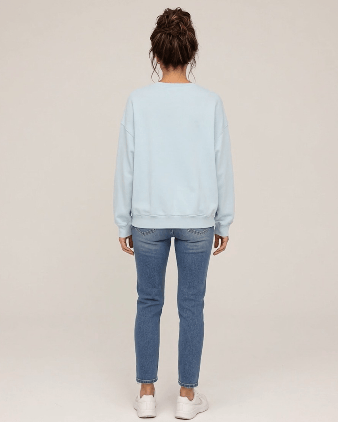 Made in USA Vintage Distressed Merry Christmas crew neck sweatshirt in light blue with a distressed charcoal MERRY CHRISTMAS graphic with PEACE JOY LOVE, back full-length view with a plain back on female model with jeans