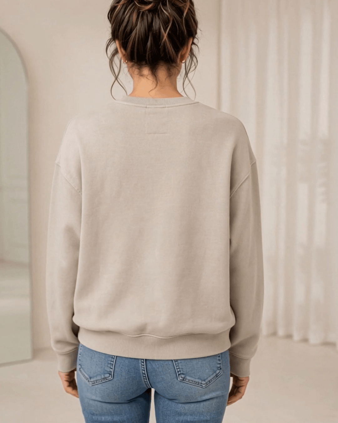 Made in USA Vintage Distressed Merry Christmas crew neck sweatshirt in taupe with a distressed charcoal MERRY CHRISTMAS graphic with PEACE JOY LOVE, back view with a plain back on female model with jeans
