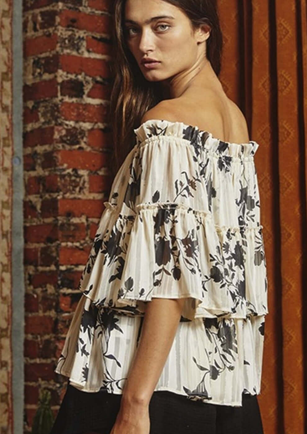 Bucket List Style# T1484 | Ladies Floral Print Tiered Off Shoulder Top with Merrow stitch detailing lurex chiffon in Cream with Black Floral Print | Made in USA